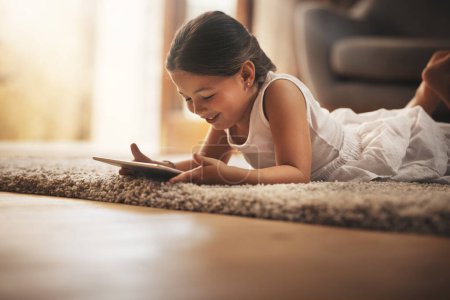 Photo for Female child, happy and playing with tablet on carpet for digital education, ebook and learning in house. German girl, smile and tech on floor for cartoon, video and movie or virtual gaming app. - Royalty Free Image