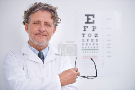 Photo for Eye, test and portrait of optometrist in clinic with glasses to check vision and exam in healthcare. Mature, doctor and reading letters on wall in medical assessment for contact lenses or eyesight. - Royalty Free Image