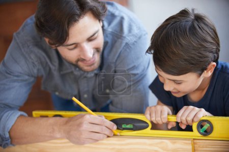 Photo for Dad, kid and woodwork pencil for project, bonding and building with safety gear. Father, son and carpenter for renovating, measuring and teaching moment for development of house with spirit level. - Royalty Free Image