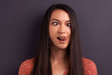 Photo for Woman, funny face and studio for comedy tongue out or mockup space, grey background or humor. Female person, model and crazy emoji as meme for comic reaction with goofy good mood, carefree or squint. - Royalty Free Image