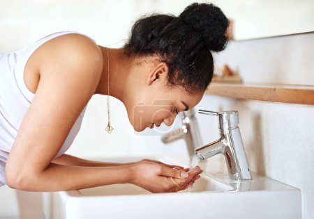 Photo for Woman, bathroom and basin for washing face, skincare and beauty for morning routine or wellness in home. Female person, tap or girl cleaning with water in house for natural facial treatment in sink. - Royalty Free Image