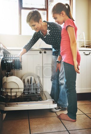 Photo for Dishwasher, mother and girl cleaning in kitchen together with help, learning or teaching. Housekeeping, mom and daughter in happy home washing dishes in machine with smile, support and morning chores. - Royalty Free Image