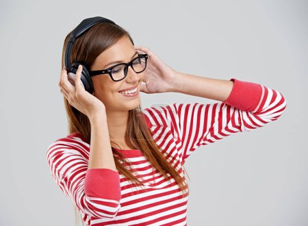 Photo for Woman, headphones and music listening in studio or streaming app as subscription, connection or entertainment. Female person, glasses and rock audio on grey background for jazz sound, track or mockup. - Royalty Free Image