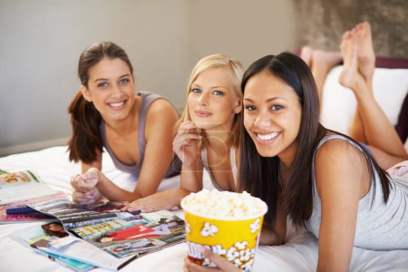 Friends, popcorn and portrait for sleepover, social and bedroom for bonding and excited group for snacks. Female people, together and magazines for jokes, besties and entertainment with conversation.