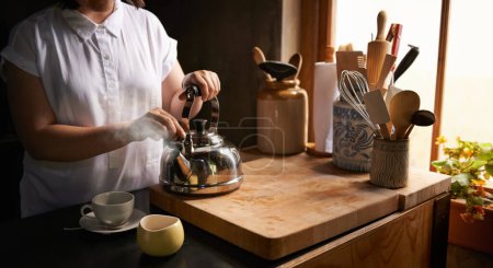 Bereiten, Tee und Morgen in der Küche mit den Händen auf Wasserkocher für den Routineprozess zu Hause. Gesund, Matcha oder Person im Haus mit Frühstücksgetränk, um in den Urlaub oder Urlaub zu starten und sich mit Getränk zu entspannen.