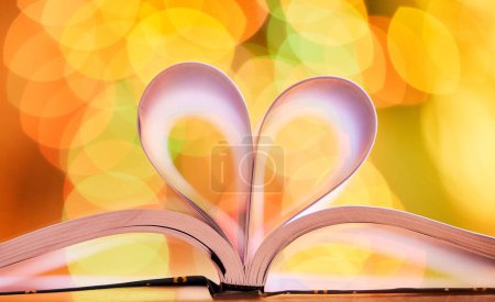 Foto de Bokeh, fondo y libro abierto con corazón por amor a la lectura, la educación y el conocimiento con luz. Color, brillante con forma o emoji para estudiar, deberes y material de aprendizaje con cuidado en papel. - Imagen libre de derechos