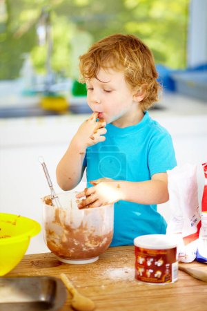 Photo for Messy, boy or eating of chocolate to play, learn or child development as growth milestone idea. Male youth, lick or fingers as playful, naughty or nutrition in holiday wellness activity in kitchen. - Royalty Free Image