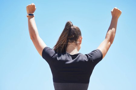 Photo for Blue sky, celebrate and back of woman for fitness, exercise and running victory outdoors. Sports, happy and person with hands up for workout, training and challenge in nature for wellness and health. - Royalty Free Image