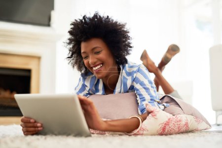 Woman, home and happy on tablet with lying on floor for social media post and entertainment. Female person, living room and smile with streaming service or website for funny videos and memes.