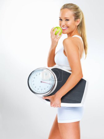 Photo for Woman, portrait and scale or apple for health, studio and excited for results of diet or detox. Female person, nutrition and journey for calories burned target, organic snack and white background. - Royalty Free Image