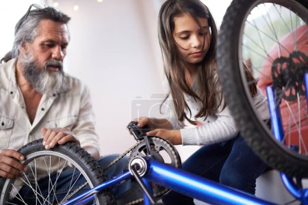 Photo for Father, child and bicycle for fixing chain as maintenance in garage for bonding together, transportation or teamwork. Mature man, daughter and equipment for bike repair or gear help, wheel or tyre. - Royalty Free Image