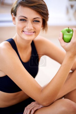 Retrato, ejercicio y mujer feliz con manzana en el gimnasio para dieta, nutrición y bienestar con cuerpo sano. Cara, forma física y sonrisa de la persona que come frutas para la vitamina C y los beneficios de los alimentos orgánicos.