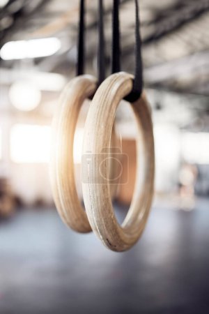 Gymnastic rings, gym and workout for exercise, fitness and strong or power challenge for training. Equipment, tool and flexibility harness or sports for wellness, arena and gear for competition.