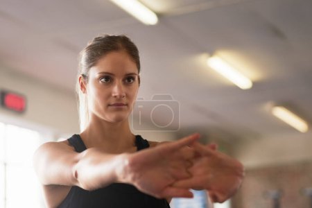 Photo for Face, fitness and stretching with sports woman in gym for health, serious workout or strength. Exercise, mindset and warm up with athlete getting ready for training to improve physical condition. - Royalty Free Image
