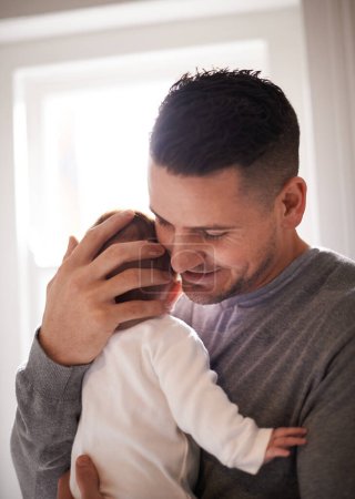 Photo for Dad, baby and pride with hug for bonding, love and happiness with child development and parenting. Peace, calm and childhood with smile, man and newborn infant for tender moment at family home. - Royalty Free Image