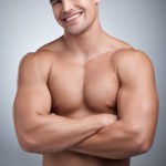 Man, muscular torso and portrait in studio for fitness, gym or workout for physical training or exercise. Model, smile and shirtless for bodybuilder and confident with muscle growth for wellness.