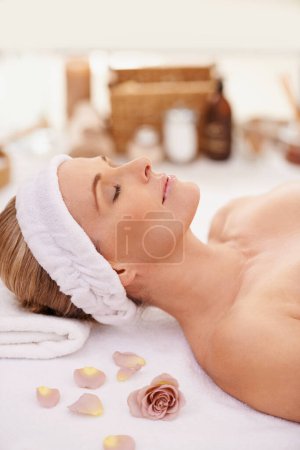 Photo for Woman, spa and rest for zen, peace and wellness with relaxation and calm. Lady, towel and massage table at resort, lounge or luxury parlor with rose for holistic body and skincare for detox and break. - Royalty Free Image