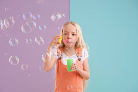 Photo for Child, blowing bubbles and playing in studio as holiday activity for leisure, childhood development or mockup space. Female person, kid and toy or split purple with blue background, innocent or fun. - Royalty Free Image