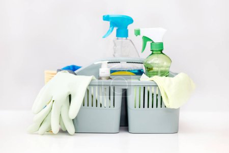 Photo for Cleaning, white background and basket with product for hygiene, disinfection and bacteria for maid service. Housekeeping, spring clean and wash tools with detergents, spray bottle and glove in studio. - Royalty Free Image
