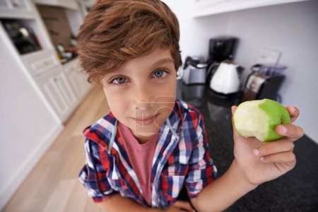 Photo for Portrait, apple and children with boy in kitchen of home for health, organic diet or nutrition. Face, fruit and confident young teen kid eating green food in apartment for growth or development. - Royalty Free Image