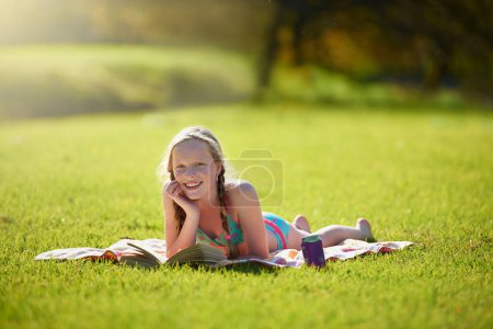 Photo for Portrait, girl or book on grass, reading or imagine by story, freedom or vacation at summer camp. Tween, novel or fiction as lying happy to wonder at idea of daydream, fantasy or sunshine at weekend. - Royalty Free Image