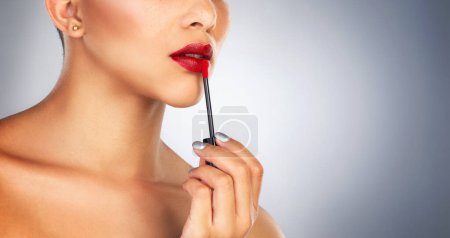 Photo for Lip brush, makeup and person in studio, red lipstick and beauty for cosmetics, glow and shine of aesthetic. Self love, color and foundation on face, application and product for model in banner. - Royalty Free Image