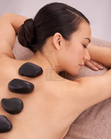 Photo for Wellness, woman and massage with hot stone therapy and skin detox with vacation and stress relief. Natural, person or girl with peace or calm with holiday or weekend break with luxury resort or relax. - Royalty Free Image