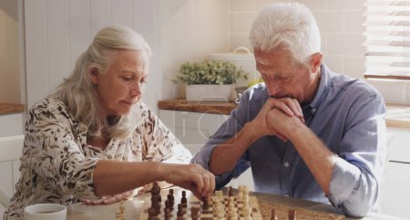 Photo for Senior, retired and couple at home with chess on board game by bonding, thinking and strategy for decision. Elderly, man and woman in kitchen with love, relax and trust for challenge of skills. - Royalty Free Image