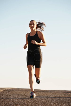 Foto de Mujer, corriendo en la calle y ejercitándose para cardio, salud y aire fresco al entrenar para maratón con fondo cielo. Deportes, ejercicio y atleta en la ciudad para entrenamiento, bienestar y resistencia al aire libre. - Imagen libre de derechos