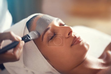 Photo for Facial, mask and cosmetic treatment for woman in spa for relax, wellness and beauty for break and skincare. Young person with eyes closed and towel on head with product on face for hygiene and care. - Royalty Free Image