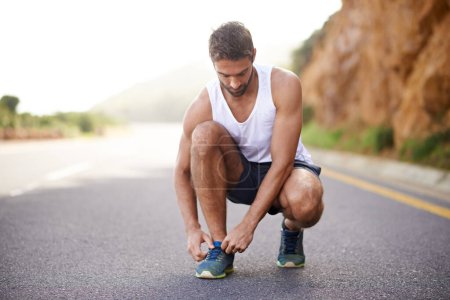 Photo for Man, runner and tying laces on road for workout, prepare and sneakers for cardio or training for marathon. Male person, feet and fitness on mountain for performance, athlete and ready for exercise. - Royalty Free Image