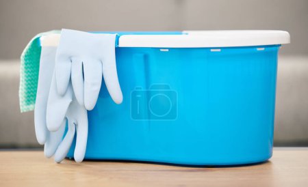 Photo for Cleaning cloth, bucket and gloves on table with materials for washing, mopping and spring clean in living room. Housekeeping, chores and supplies for hygiene, sanitation and cleanliness in home. - Royalty Free Image