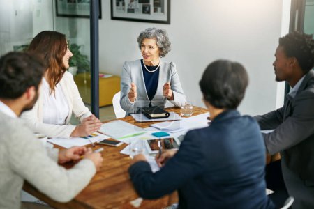 Photo for Business people, talking or mature woman in meeting for planning, collaboration or teamwork at office. Group, female mentor or investors with strategy for discussion, conversation or feedback review. - Royalty Free Image