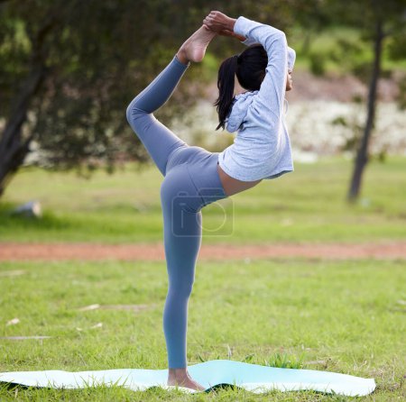 Téléchargez les photos : Yoga, équilibre et femme indienne s'étirant dans le parc pour le bien-être, le corps sain et se réchauffer dans la nature. Pilates, fitness et personne sur tapis, gazon et pelouse pour l'exercice, l'entraînement et l'entraînement à l'extérieur. - en image libre de droit