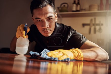 Photo for Apartment, cleaning and man with disinfectant for kitchen counter, housekeeping and bacteria. Person, home and guy with spray bottle, cloth and routine with germaphobe, remove dust and chore with ocd. - Royalty Free Image
