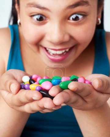 Girl, candy in hands and happy with snack for reward or bonus, shock or omg with winner of junk food. Sweets, jelly beans and excited kid for prize with joy, surprise or wow reaction with confection.