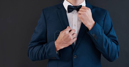 Photo for Fixing bowtie, man and hands in suit for professional, salesman or groom in studio. Gentleman, formal fashion and black background for job interview, business and financial advisor in corporate. - Royalty Free Image