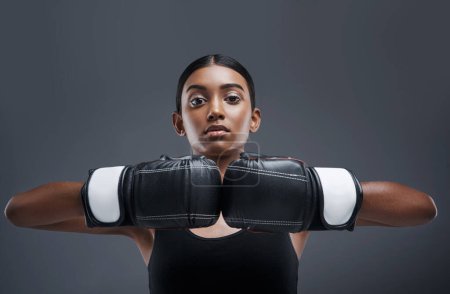 Photo for Portrait, girl and boxing gloves in studio, training and sport for exercise, fitness and Indian boxer. Workout, isolated and battle or mma, strong in dark background for fight, power and challenge. - Royalty Free Image