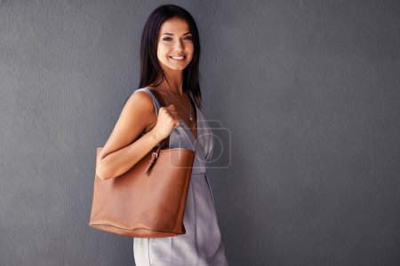Photo for Studio, portrait and handbag with fashion, joy and accessories with dress and smile. Woman, face and model with confidence, beauty and happiness with purse and style isolated on gray wall background. - Royalty Free Image