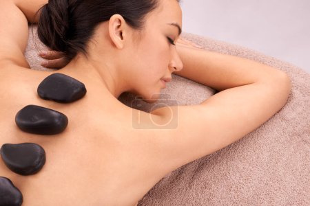 Photo for Relax, woman and massage with hot stone therapy and wellness with weekend break and stress relief. Natural, person and girl with peace or spa with holiday and rocks with skin detox or luxury resort. - Royalty Free Image