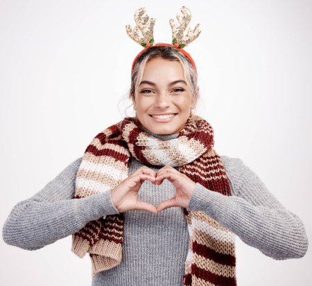 Photo for Christmas, woman and heart with smile in portrait for festive, winter and holiday on studio backdrop. Female person, cheerful and happy in celebration with shape for love in season for vacation. - Royalty Free Image