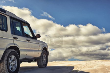 Photo for Dunes, vehicle and sky with clouds, adventure and transport on road trip for holiday. Outdoor, sand and 4x4 for travel in Dubai for desert landscape, nature and truck in sunshine and wilderness. - Royalty Free Image