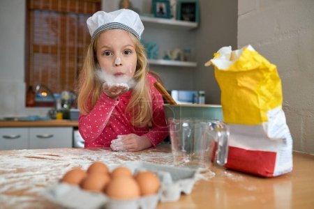 Photo for Happy, child or young chef portrait baking in kitchen for learning, practice or making dessert. Fun, chaos and girl mixing flour or ingredients in bowl with energy and excitement for home made treat. - Royalty Free Image