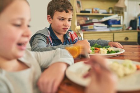 Photo for Child, eating and upset with healthy food in home with vegetables, nutrition and angry with diet. Hungry, kid and frustrated with plate of potatoes, salad and dislike for dinner with broccoli. - Royalty Free Image