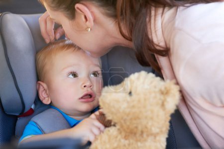 Photo for Travel, safety and mom with baby in car seat on road trip, journey or motor security insurance. Child, lock and seatbelt in vehicle for transport protection and kiss kid with teddy bear and toys. - Royalty Free Image