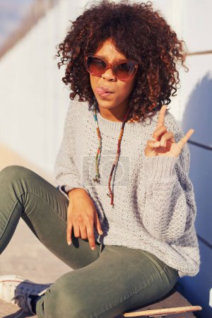 Photo for Woman, fashion and portrait with skateboard in city for skate, crazy and break in urban for summer, fun and silly. African person and tongue out with shades for happy, trendy and cool for funky. - Royalty Free Image