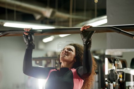 Fitness, woman and pull up exercise at gym on bar for muscle, wellness or healthy body. Chin up, training and strong female person with equipment at club for power, workout and sports for bodybuilder.