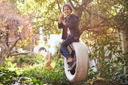 Boy, tyre swing and portrait in garden with happiness, playing and countryside vacation in summer. Child, face and diy adventure playground in backyard of home with sunlight, trees or smile in nature.