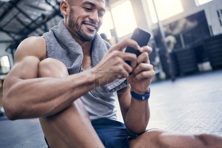 Photo for Fitness, app and man in gym with phone to post progress of exercise, schedule and planning training. Happy, body builder and person reading smartphone with health info or track development in workout. - Royalty Free Image