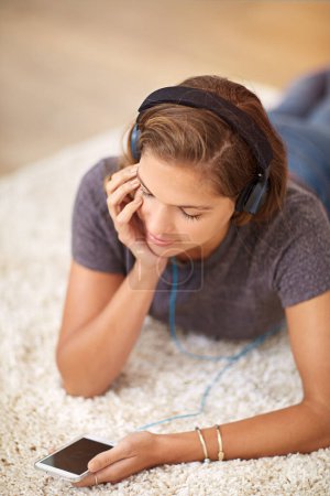 Photo for Carpet, headphones or woman with phone for music streaming, subscription or wellness in home. Smile, girl or female person listening to audio, track or song to relax on floor on mobile app for peace. - Royalty Free Image